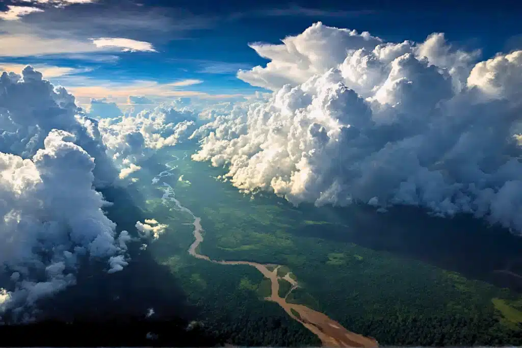 Natureza e Meio Ambiente: 8 Passos Para Aplicar ao Cotidiano 4 Vista aérea da Amazônia com vapor d'água formando nuvens acima do dossel verde, ilustrando o ciclo hidrológico e os rios voadores brasileiros.