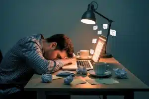 essoa exausta na frente do computador representando produtividade tóxica e esgotamento profissional